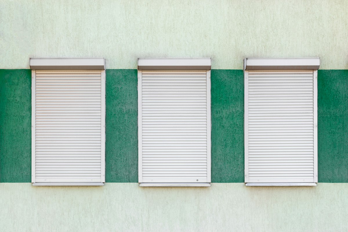 Drei geschlossene helle Rollläden an einer Hausfassade